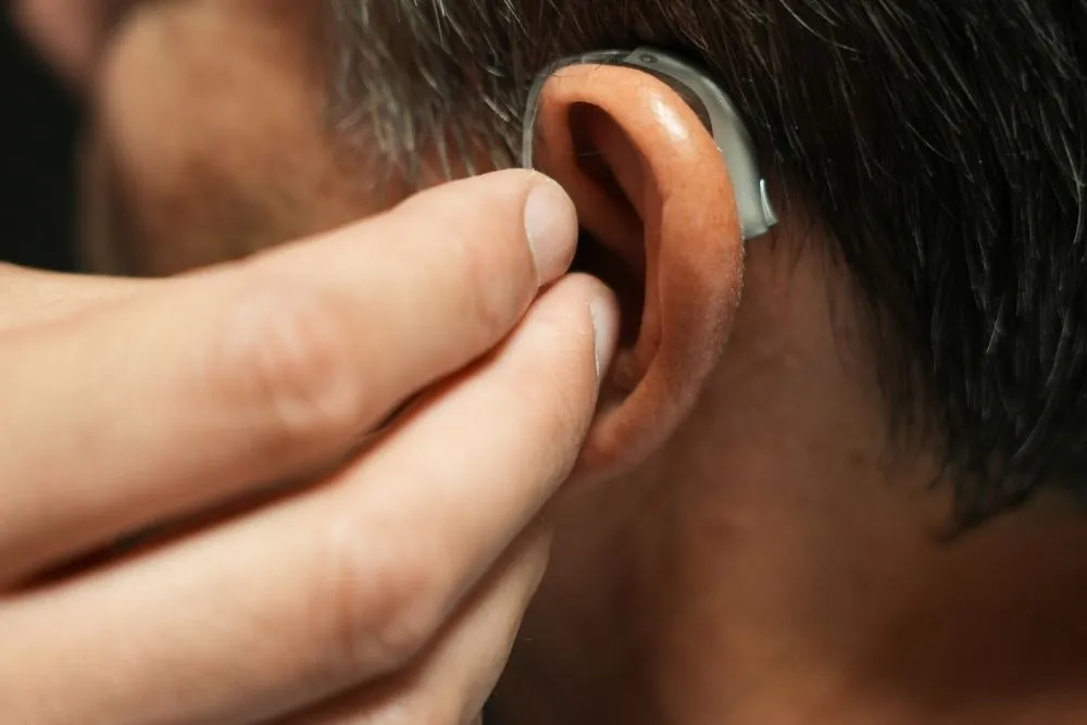Primer plano de un audífono retroauricular colocado en el oído de un hombre