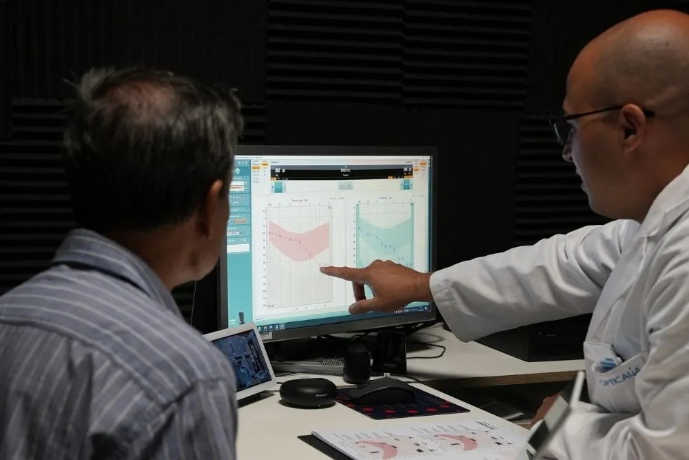 Audioprotesista de Opticalia mostrando los resultados de una audiometría en pantalla a un paciente mayor