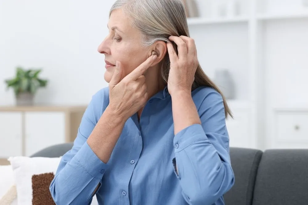 Mujer mayor colocándose un audífono retroauricular